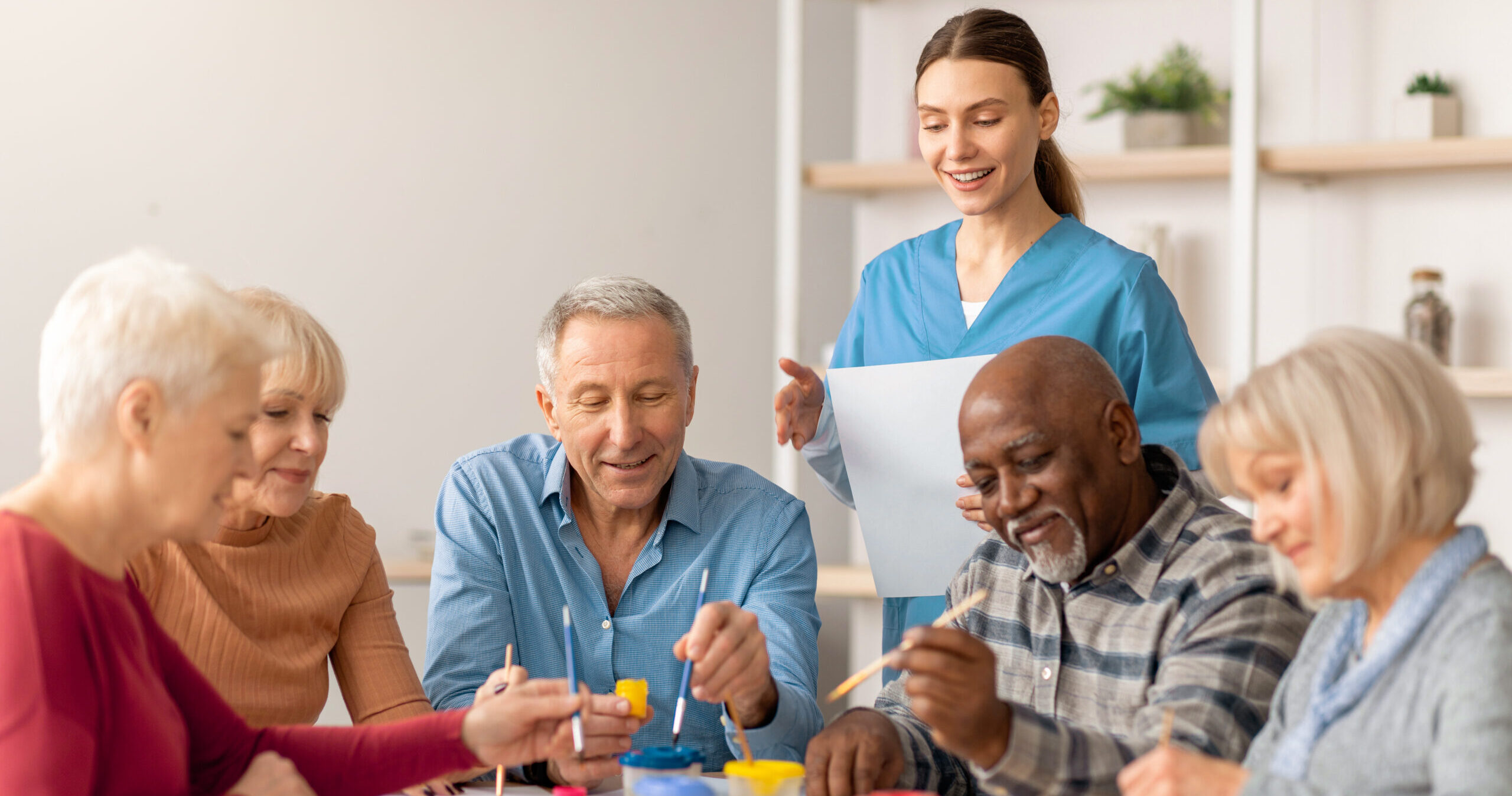 Group of happy seniors painting together in a senior living community.
