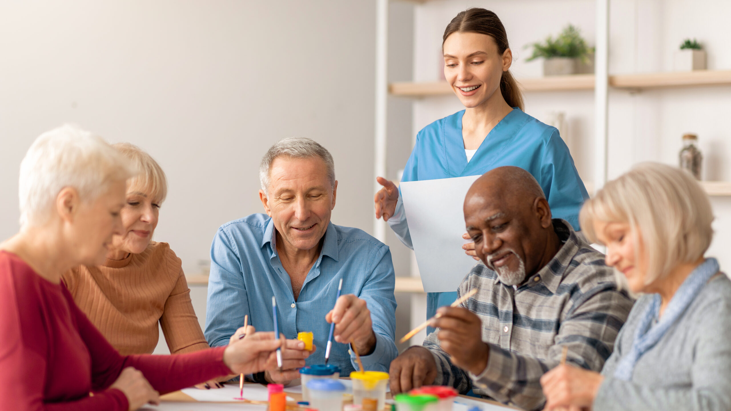 Group of happy seniors painting together in a senior living community.