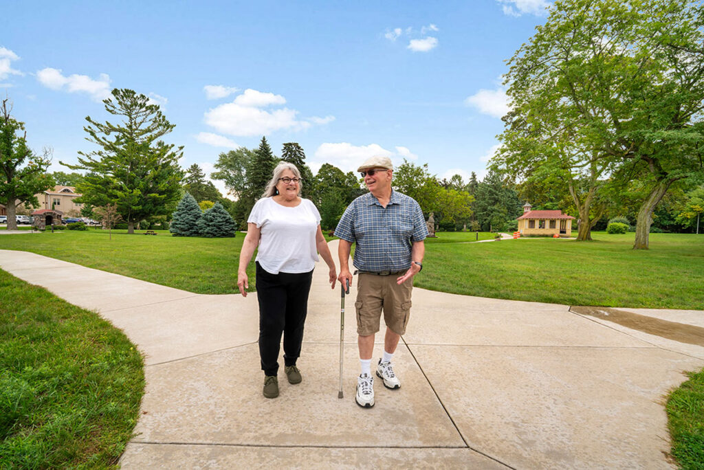 Two happy seniors taking a stroll along walking paths outside senior living community