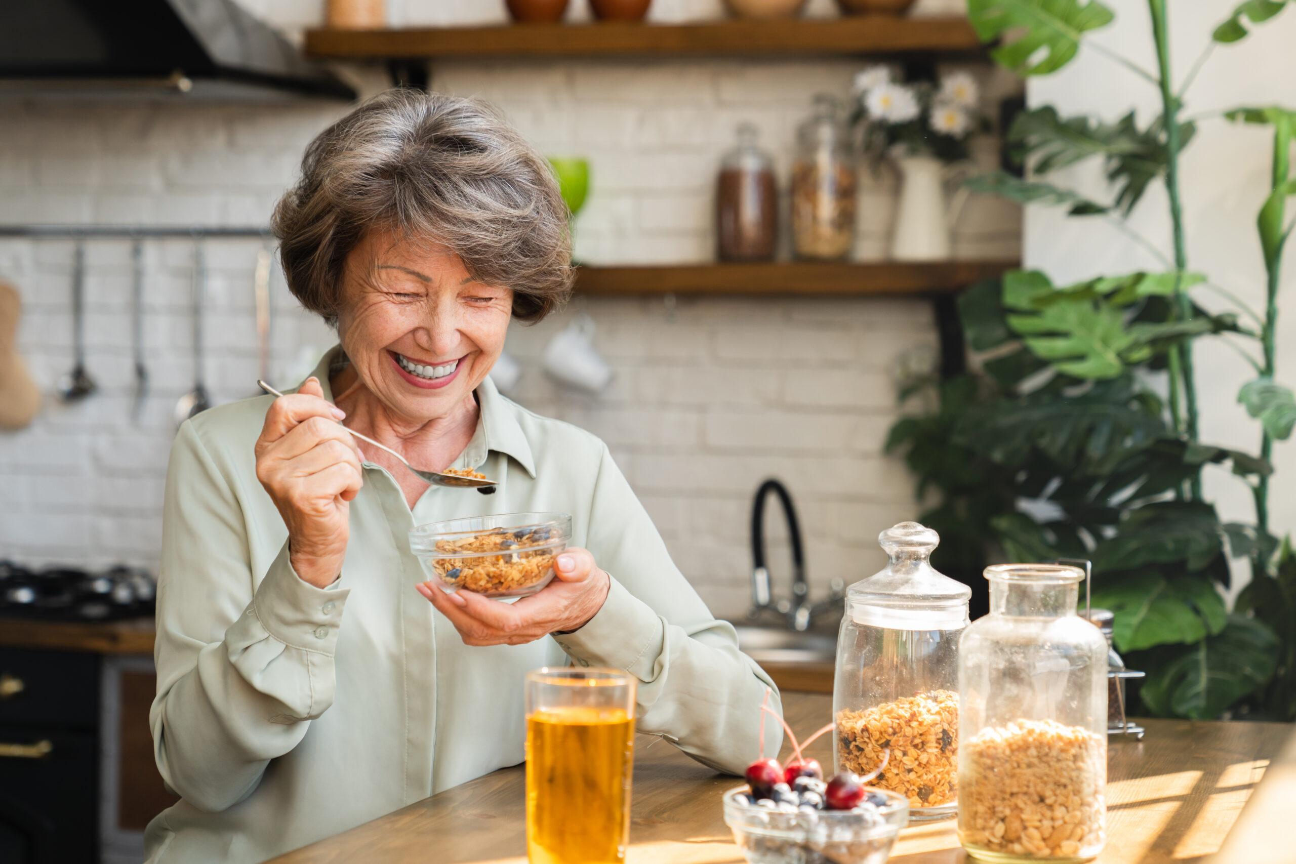 A smiling elderly women enjoying her morning breakfast and showing early signs of cognitive decline and dementia