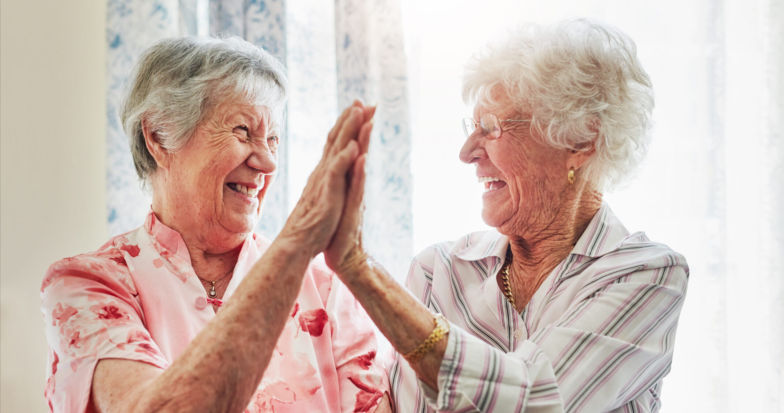 Two senior women becoming friends and bonding with a high-five.