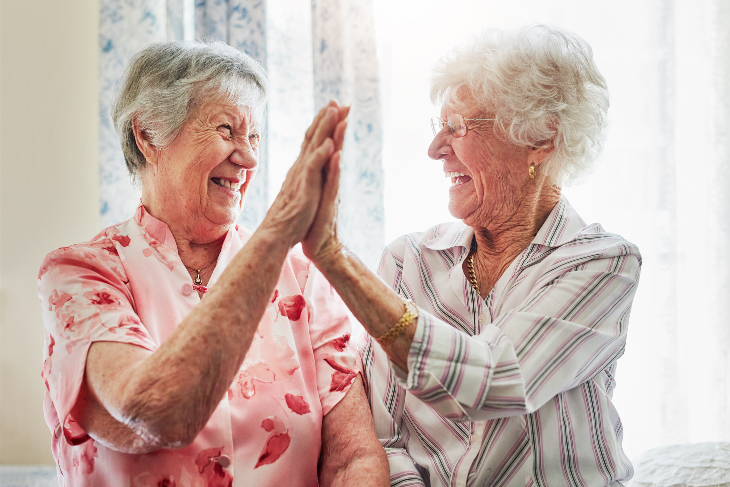 Two senior women becoming friends and bonding with a high-five.