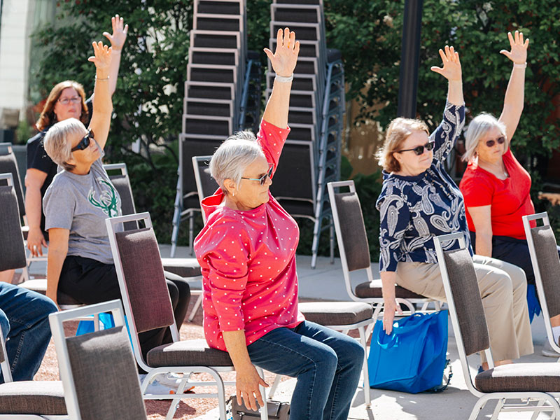 A group of people sitting in chairs with their hands up.