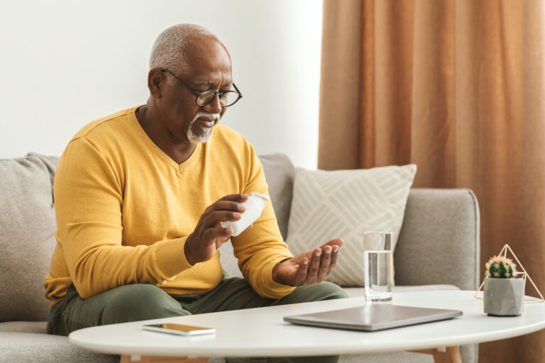 Elderly gentleman looking through his pill box at his supplements and vitamins.