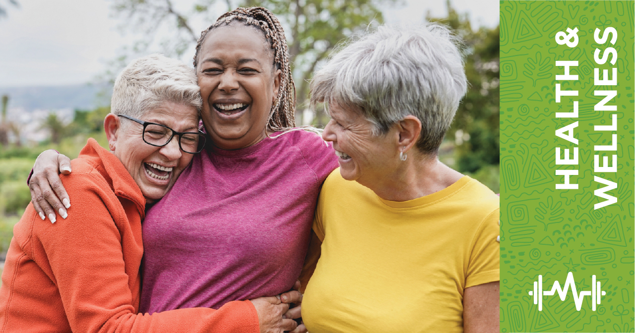 Three older women smiling and embracing each other outdoors. A green banner on the right side reads Health & Wellness.