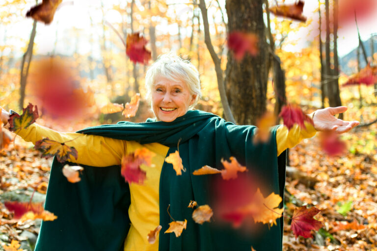 Elderly women playing in the falling leaves.