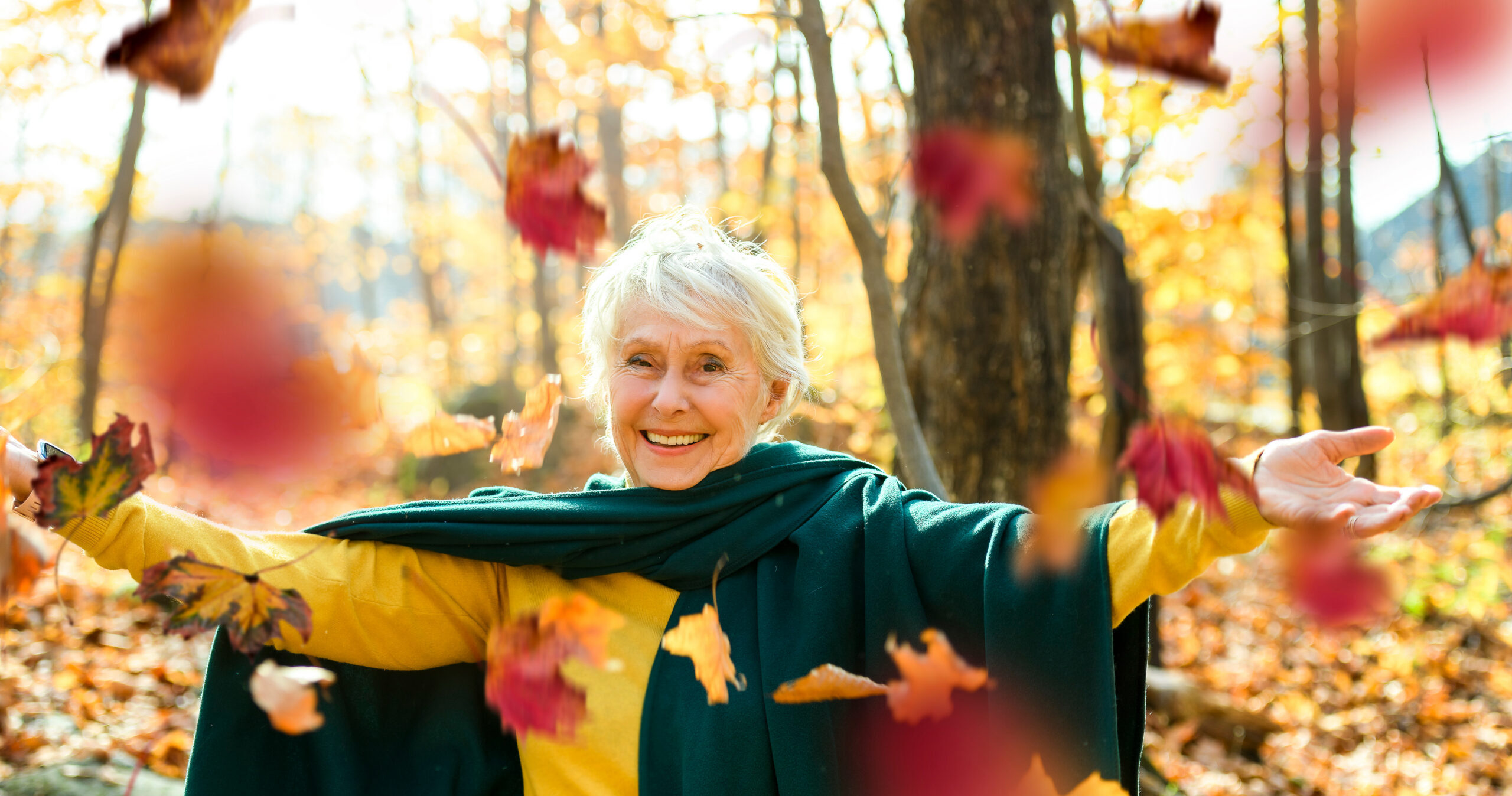 Elderly women playing in the falling leaves.