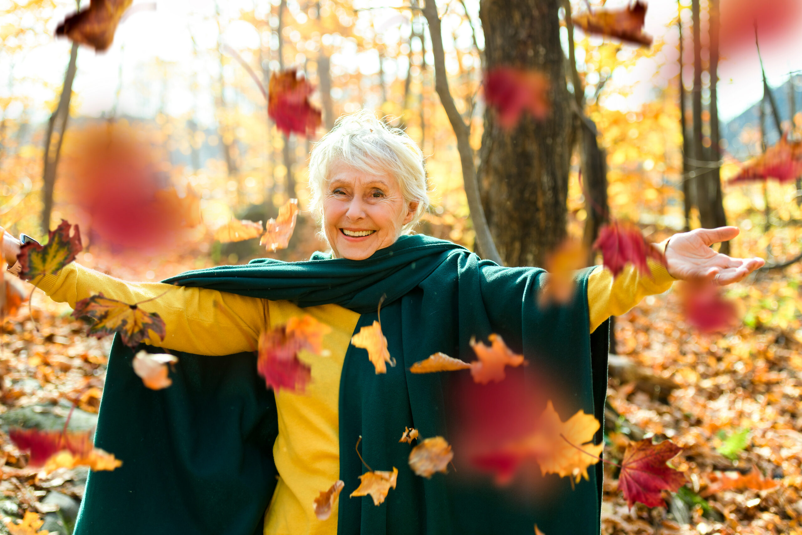Elderly women playing in the falling leaves.